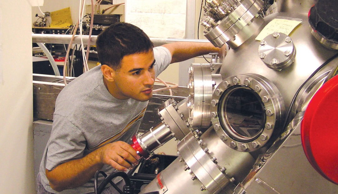 An undergraduate man looks at a large machine a lab