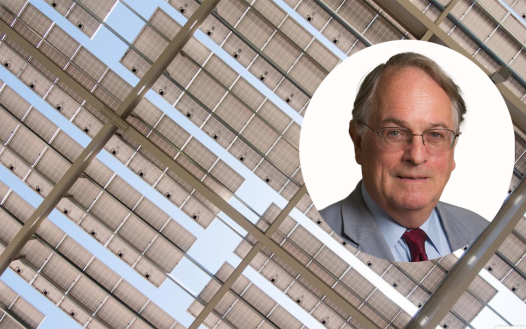 Portrait of Stanley Whittingham in front of background of solar panels.