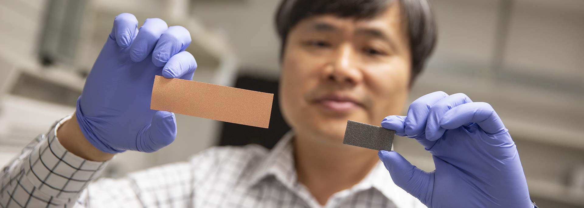 Professor holding up two different materials samples and comparing them.