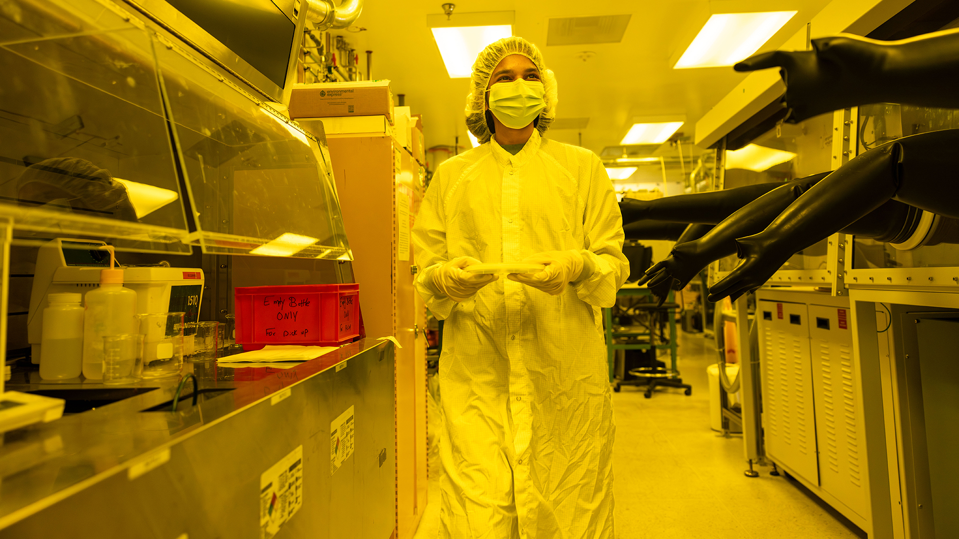 ASU electrical engineering master’s student Shreenidhi Anand walks through a cleanroom holding a wafer at MacroTechnology Works. Photographer: Samantha Chow/ASU